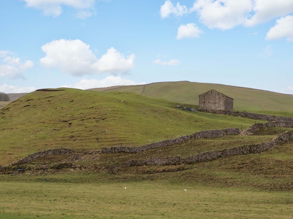 A building on a hill surrounded by grass and stone walls at Kirk Yett in Skipton