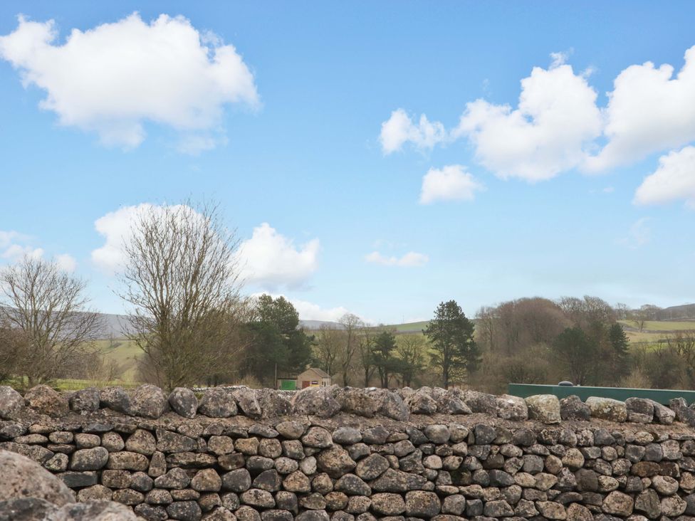 A view of a stone wall with trees and clouds at Kirk Yett in Skipton