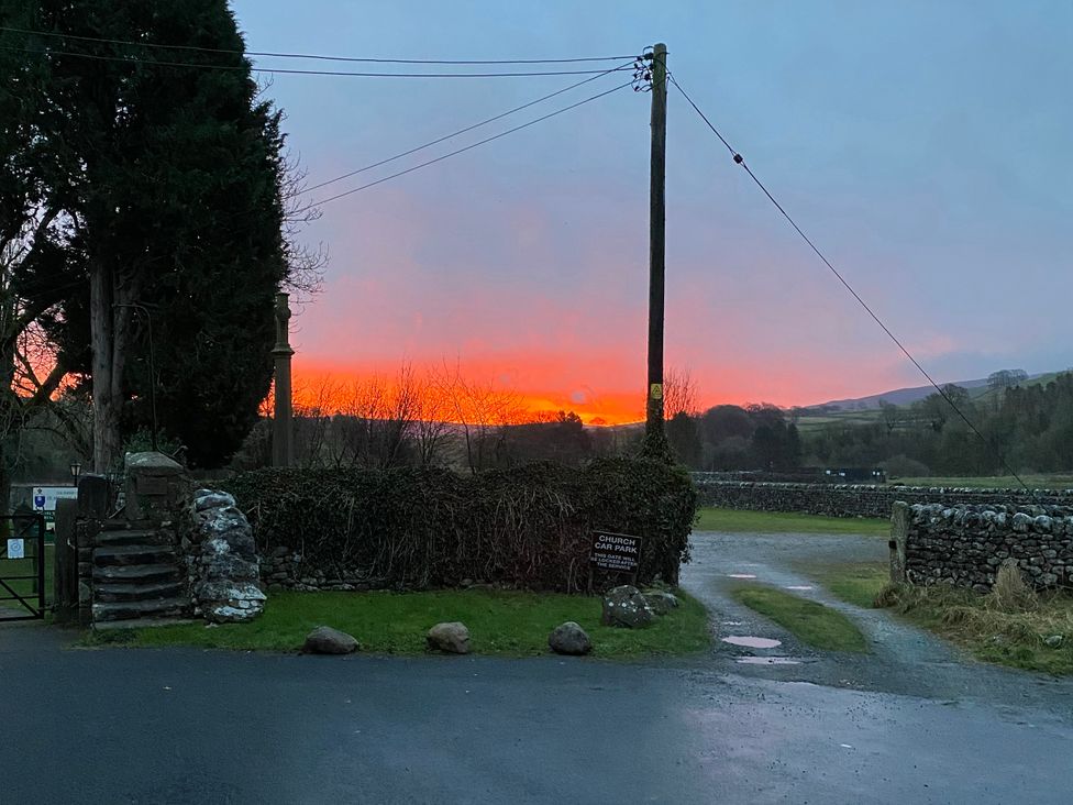 A view of a sunset with stone walls and a sign at Kirk Yett in Linton Falls near Skipton