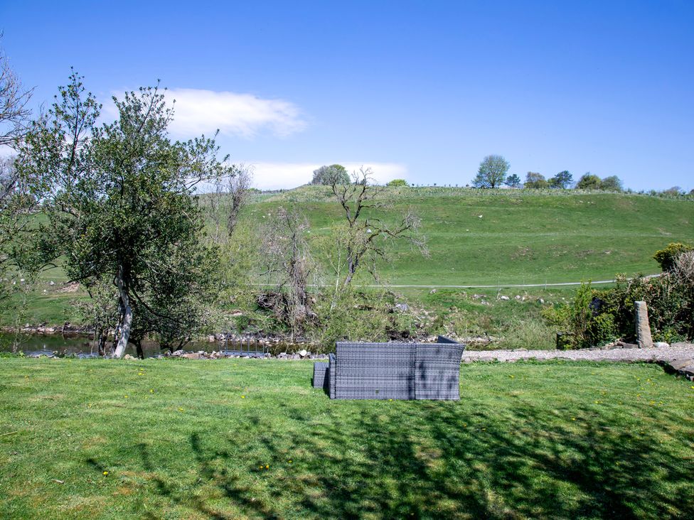 A garden with a bench and trees at Kirk Yett in Linton Falls near Skipton