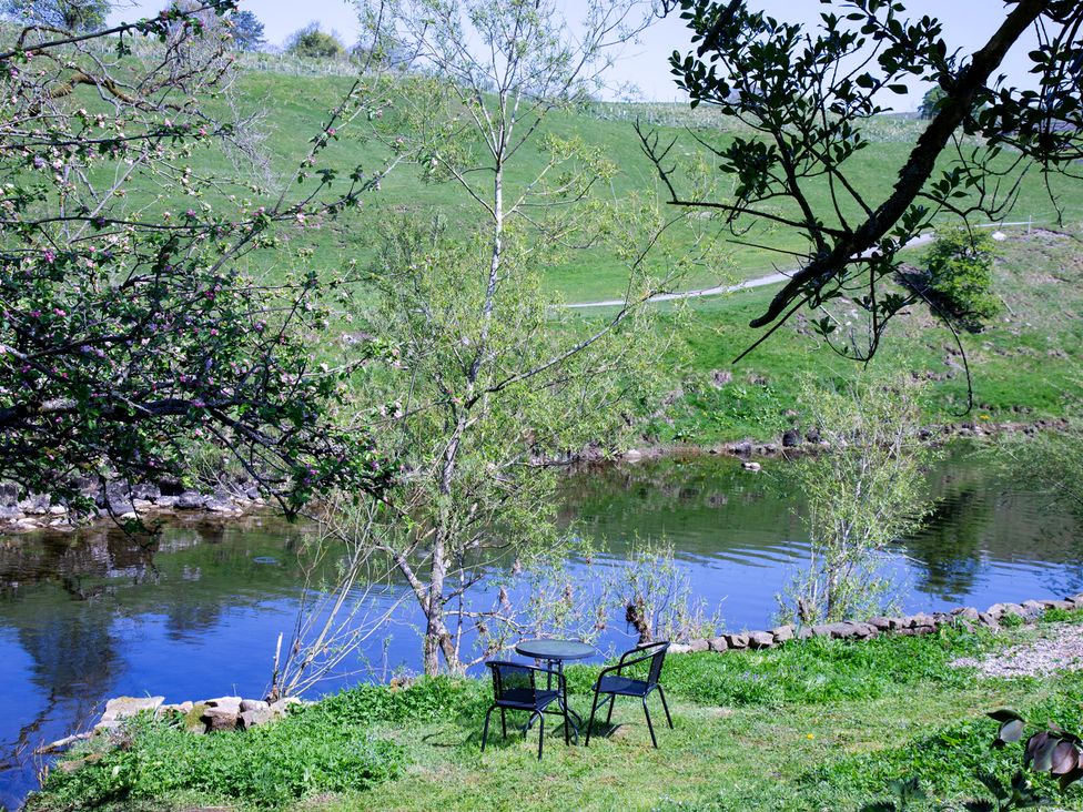 A table and chairs by a river at Kirk Yett in Linton Falls near Skipton