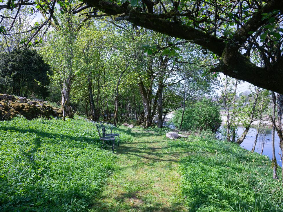 A garden path with a bench near a river at Kirk Yett in Linton Falls near Skipton