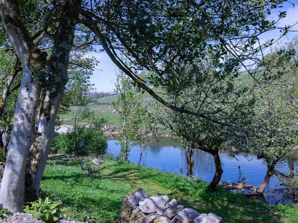 A riverside area with trees and a chair at Kirk Yett in Linton Falls near Skipton