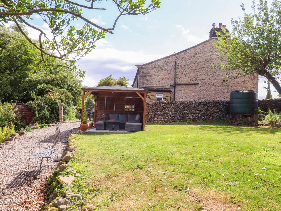 A garden with a seating area and water tank at Kirk Yett in Linton Falls near Skipton