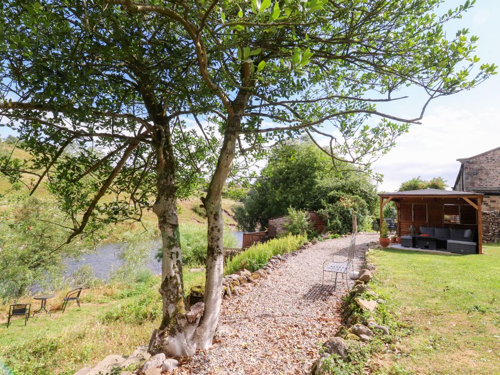 A garden with a path and river at Kirk Yett in Linton Falls near Skipton