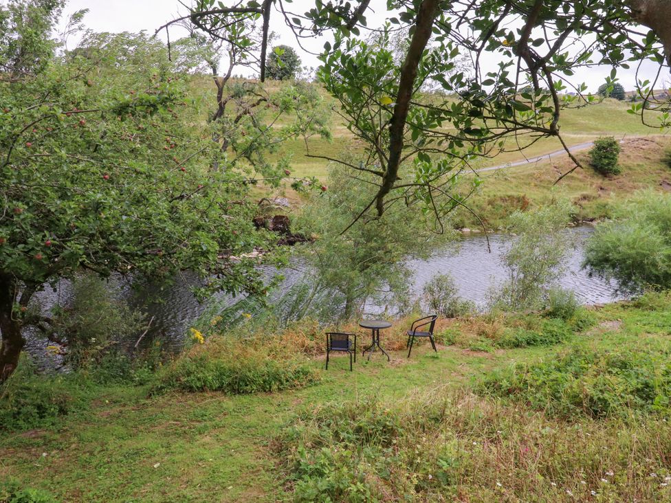 A table and chairs beside a river in an outdoor area at Kirk Yett in Linton Falls near Skipton