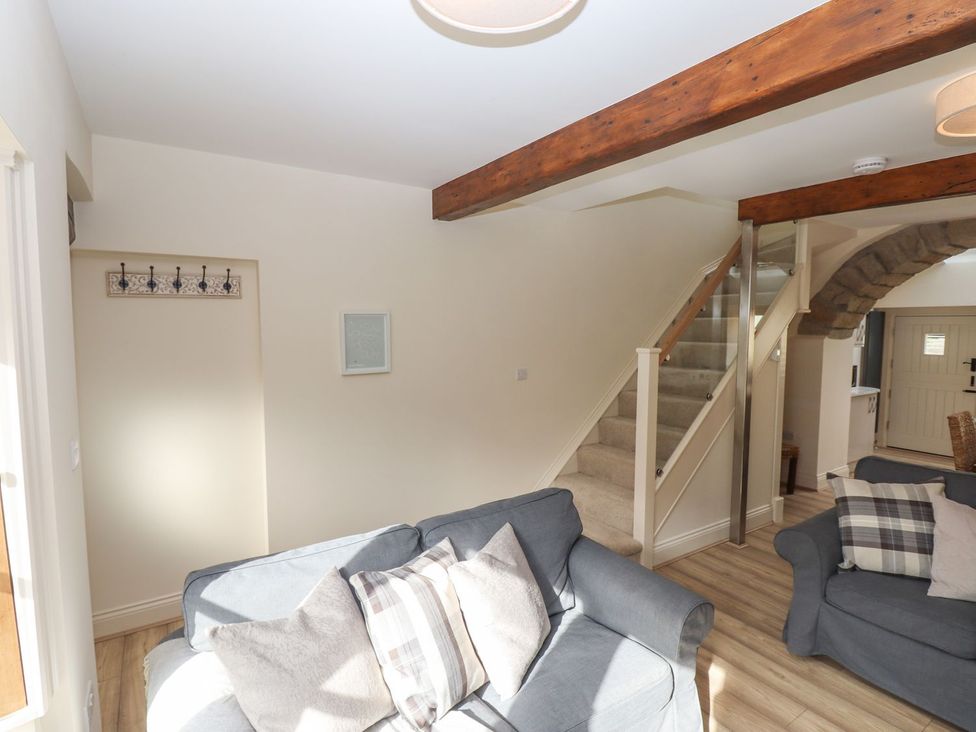 A living room with a staircase and sofa at 1 Grosvenor Farm Cottages in Skipton