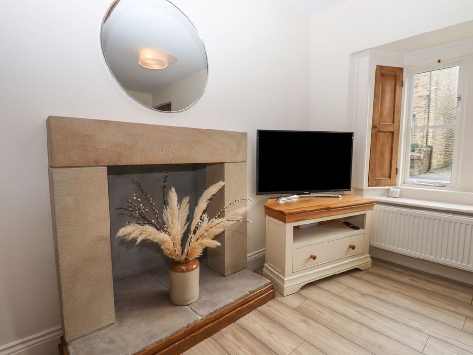 A living room with a fireplace and television at 1 Grosvenor Farm Cottages in Skipton