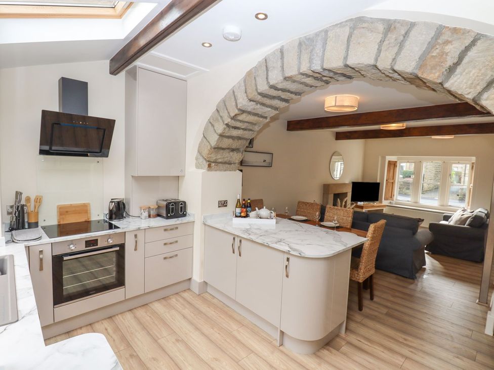 A kitchen with an island and living area at 1 Grosvenor Farm Cottages in Skipton