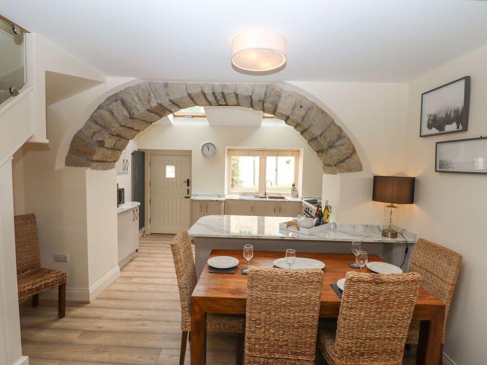 A kitchen with a dining area and stone archway at 1 Grosvenor Farm Cottages in Skipton