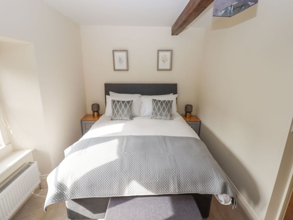 A bedroom with a bed and bedside tables at 1 Grosvenor Farm Cottages in Skipton