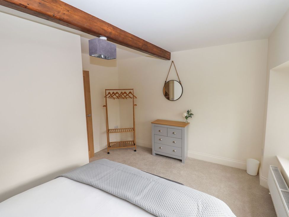 A bedroom with a bed and dresser at 1 Grosvenor Farm Cottages in Skipton