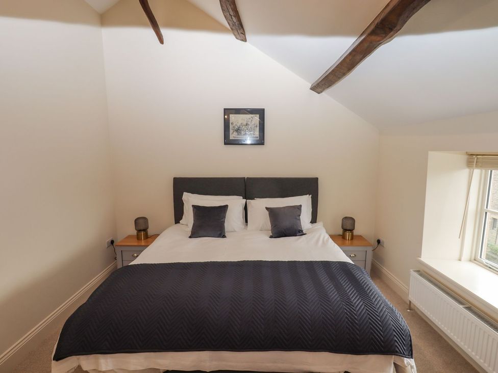 A bedroom with a bed and bedside tables at 1 Grosvenor Farm Cottages Skipton