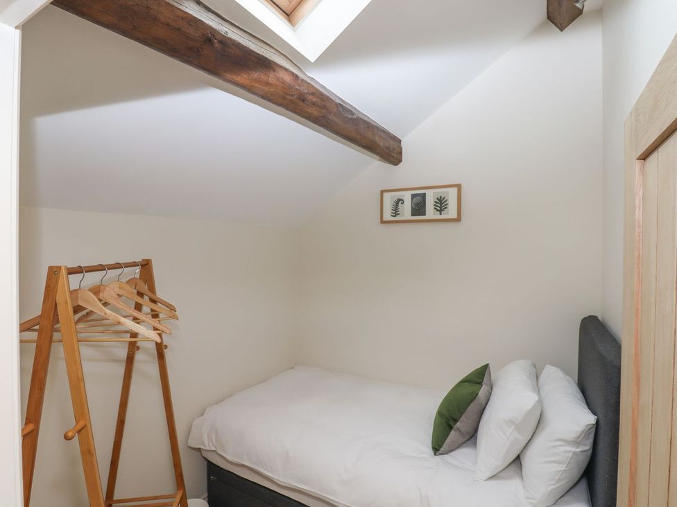 A bedroom with a bed and a wooden rack for hangers at 1 Grosvenor Farm Cottages in Skipton