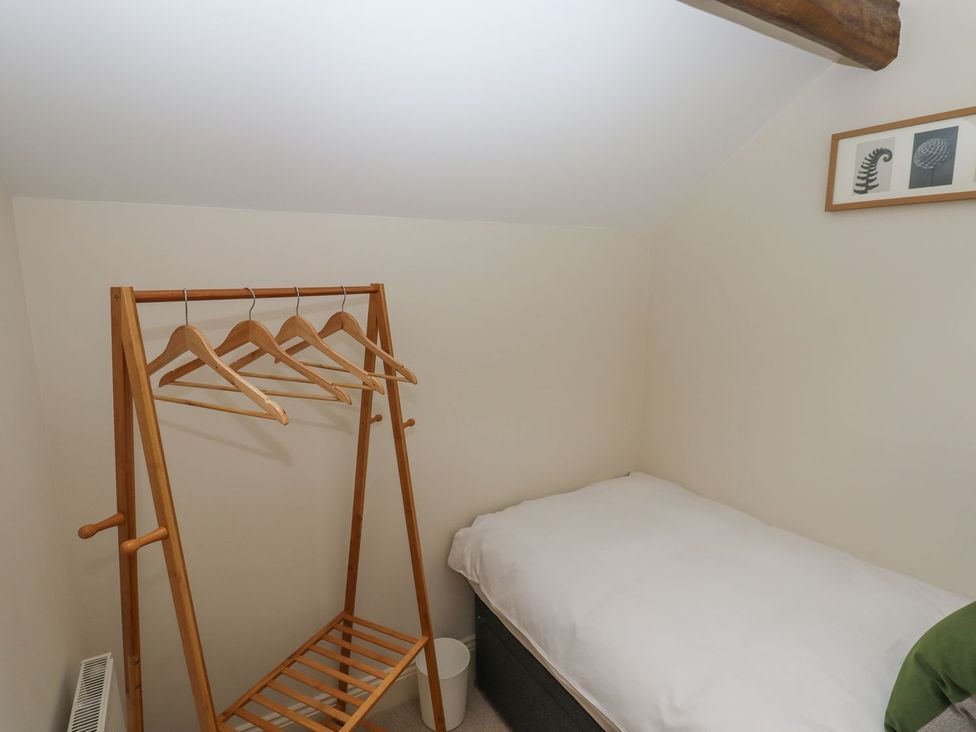 A bedroom with a clothes rail and bed at 1 Grosvenor Farm Cottages Skipton