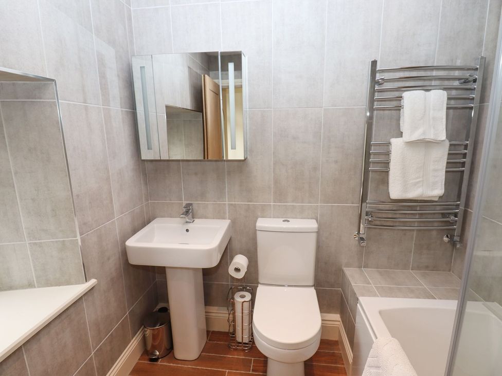A bathroom featuring a sink, toilet, mirror, and towel rail at 1 Grosvenor Farm Cottages in Skipton