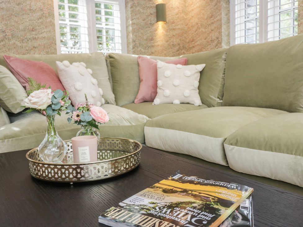 A living room with a sofa and flowers on a table at Low House Cottage Ayside near Newby Bridge