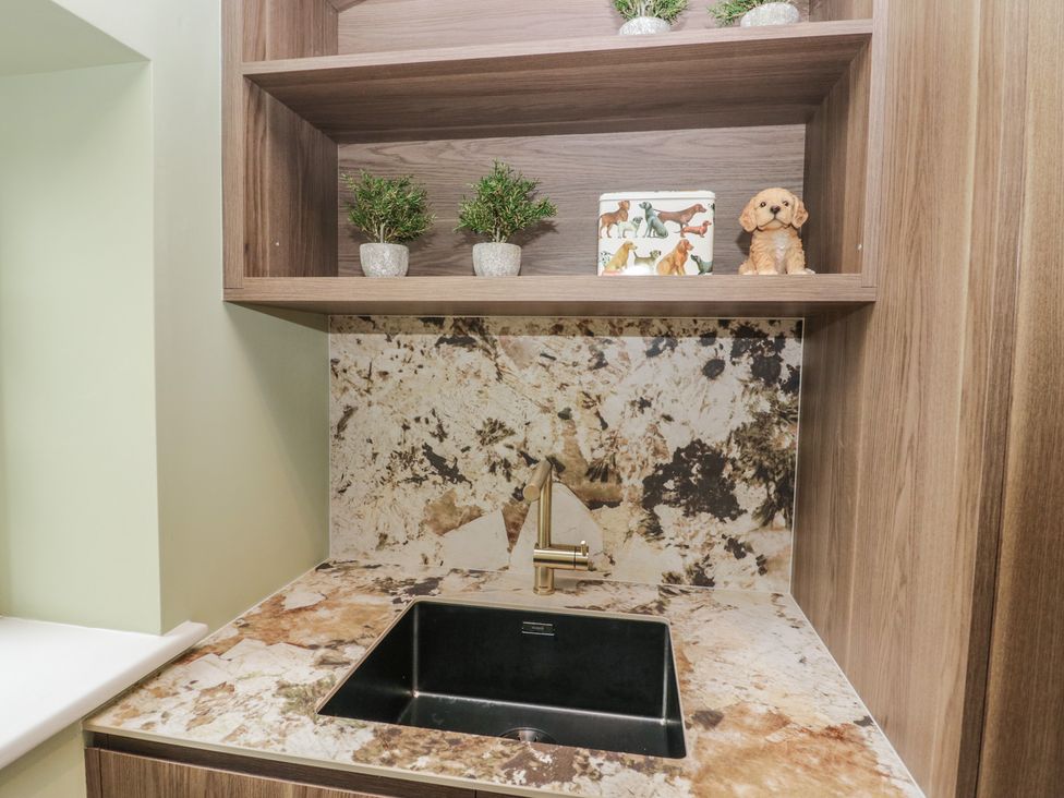 A kitchen with a sink and shelf displaying decor at Low House Cottage Ayside near Newby Bridge
