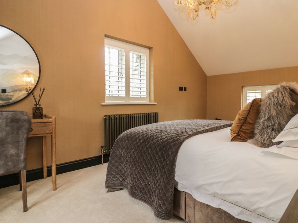 A bedroom with a bed, chair, and mirror at Low House Cottage Ayside near Newby Bridge