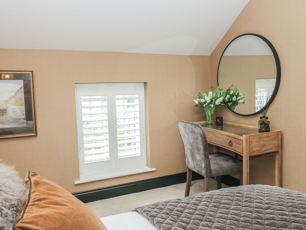 A bedroom with a desk and flowers at Low House Cottage Ayside near Newby Bridge