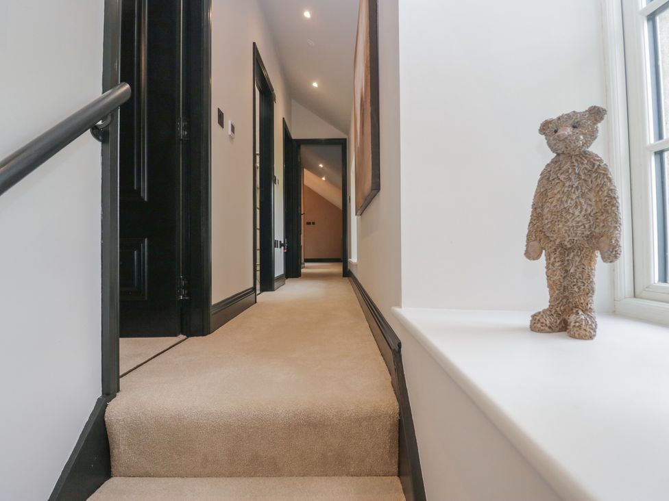A hallway with a staircase and a bear figure at Low House Cottage Ayside near Newby Bridge