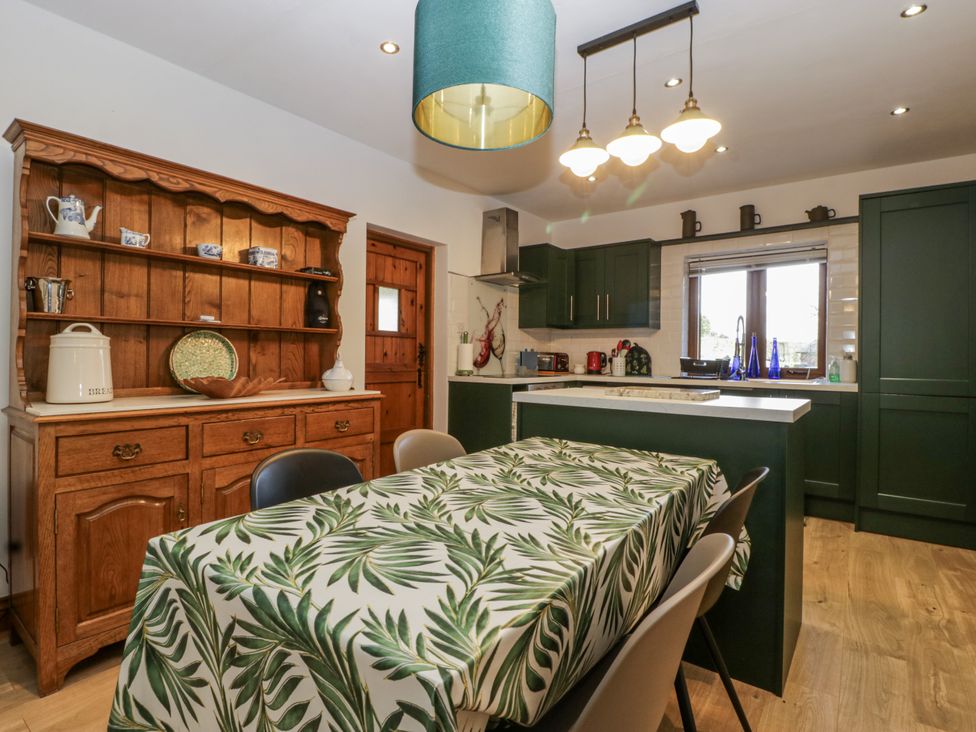 A kitchen with a dining table and shelves at The Wren's Nest in Ross-on-Wye