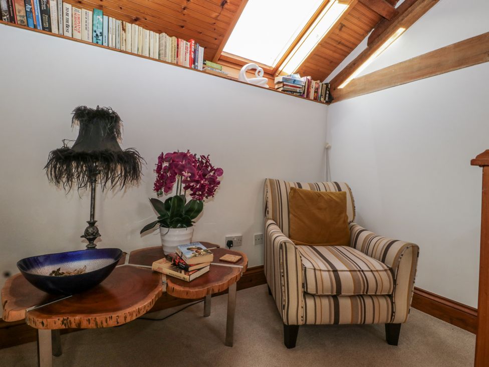 A sitting room with a striped chair and lamp at The Wren's Nest in Ross-on-Wye