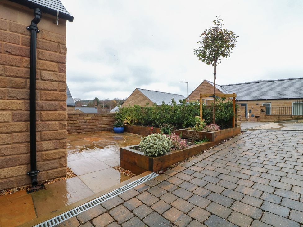 An outdoor space with paving and flower beds at Oakwood Mews Matlock