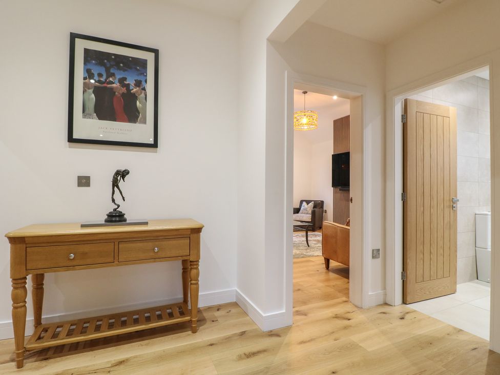 A hallway with a console table and framed artwork at Oakwood Mews in Matlock