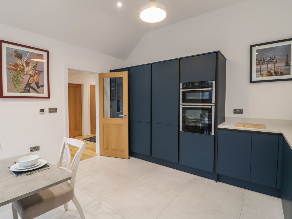 A kitchen with blue cabinets and an oven at Oakwood Mews Matlock