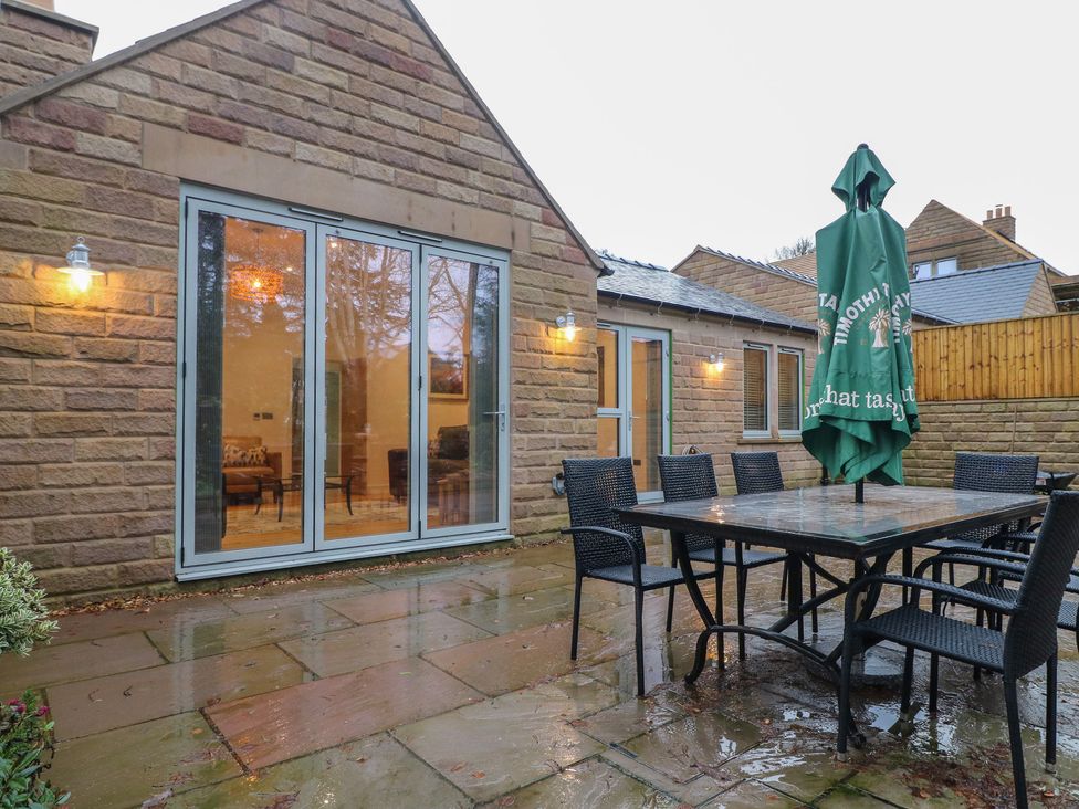 A garden with a table and chairs under a parasol at Oakwood Mews Matlock