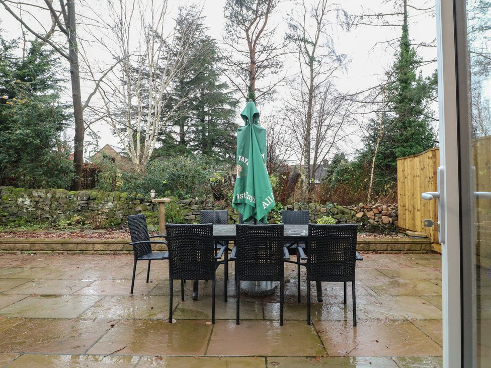 A garden with a table and chairs under an umbrella at Oakwood Mews Matlock