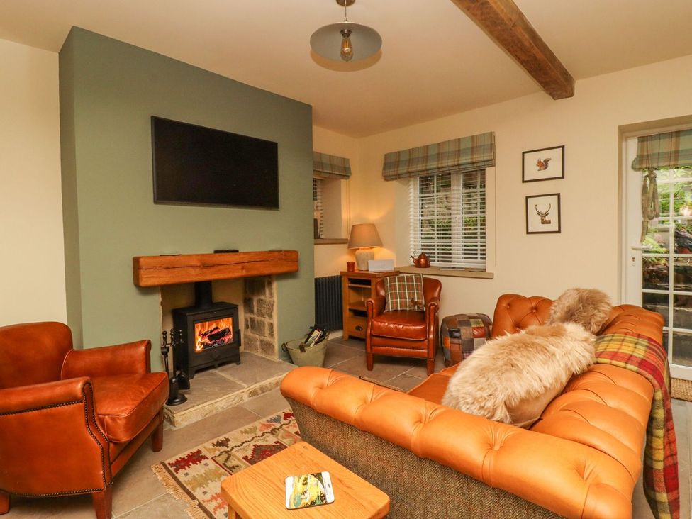 A living room with a sofa and television at Bridge House Cottage in Burn Bridge near Harrogate