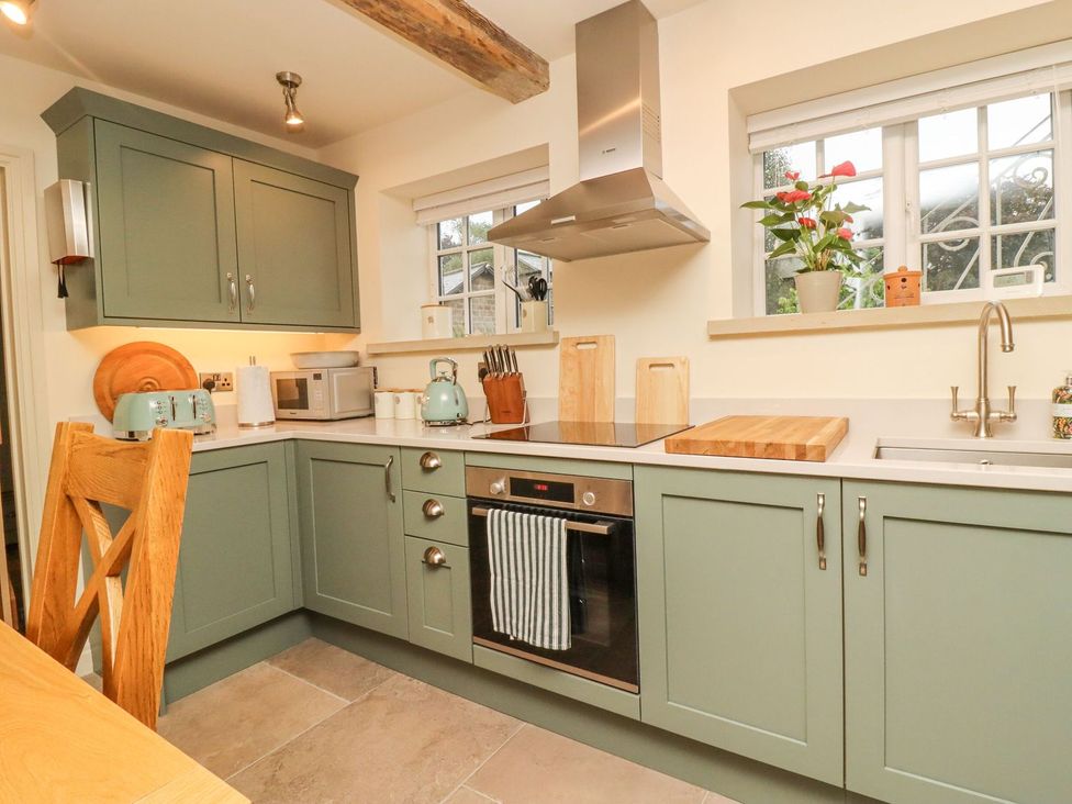 A kitchen with cabinets, oven, and sink at Bridge House Cottage in Burn Bridge near Harrogate