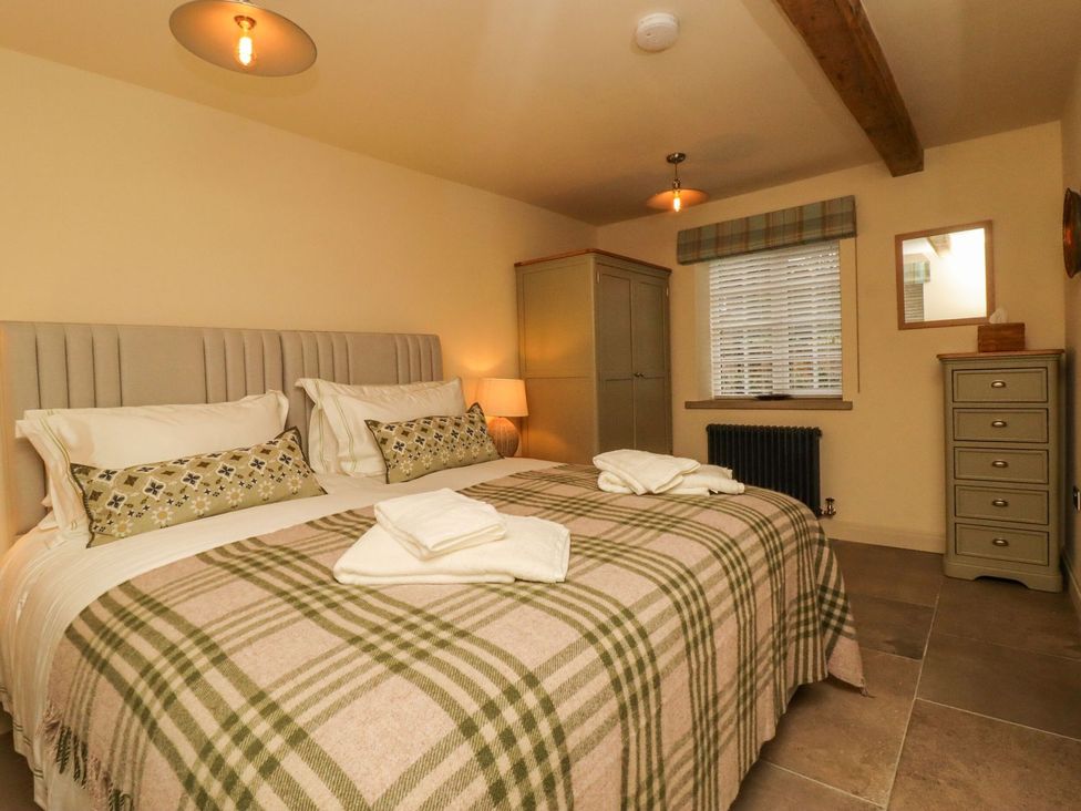 A bedroom with a double bed and storage furniture at Bridge House Cottage Burn Bridge near Harrogate