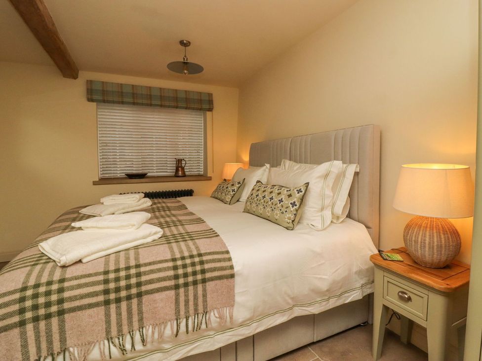 A bedroom with a bed and nightstand at Bridge House Cottage Burn Bridge near Harrogate