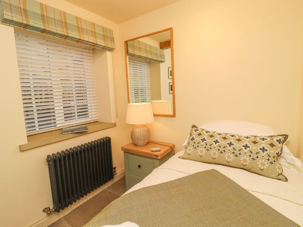 A bedroom with a bed and lamp at Bridge House Cottage in Burn Bridge near Harrogate