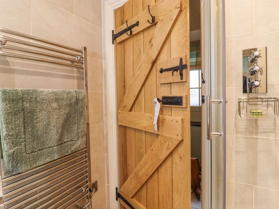 A bathroom with a towel radiator and wooden door at Bridge House Cottage Burn Bridge near Harrogate