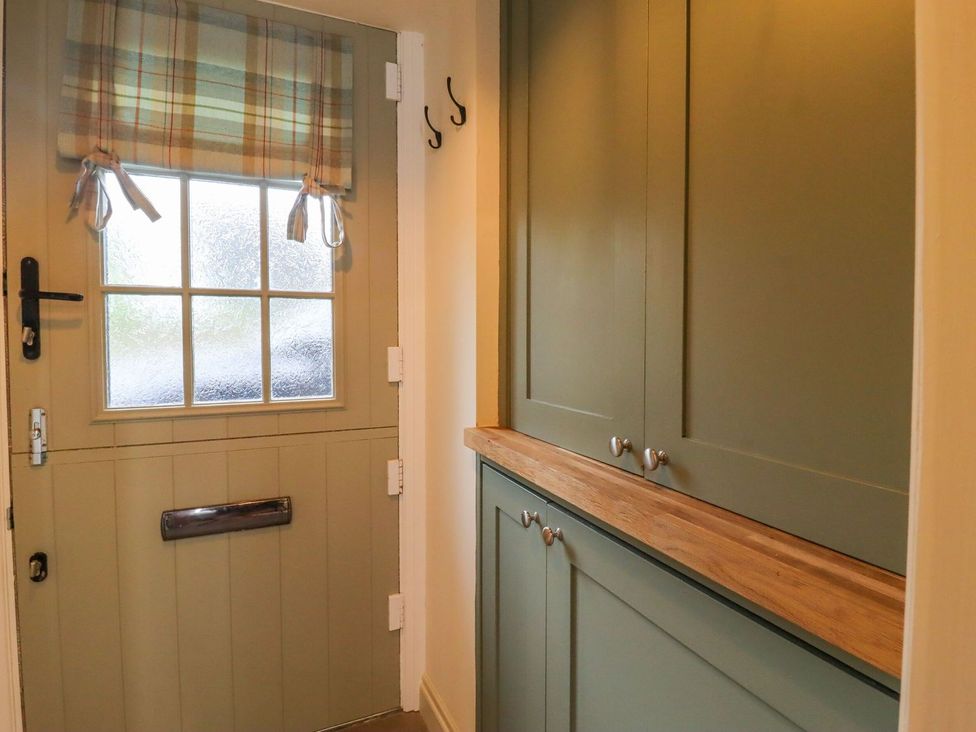 A hallway with a door and cabinet at Bridge House Cottage in Burn Bridge near Harrogate