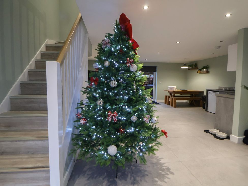 A Christmas tree near a staircase and dining area at Willow Barn Chester