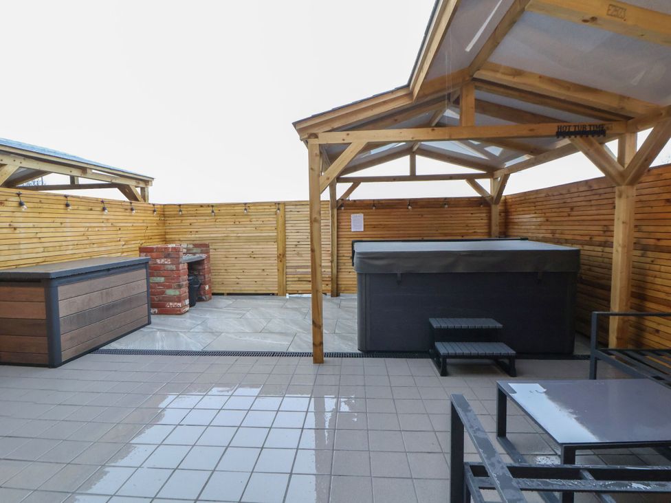 An outdoor area with a hot tub and wooden gazebo at Willow Barn in Saughall