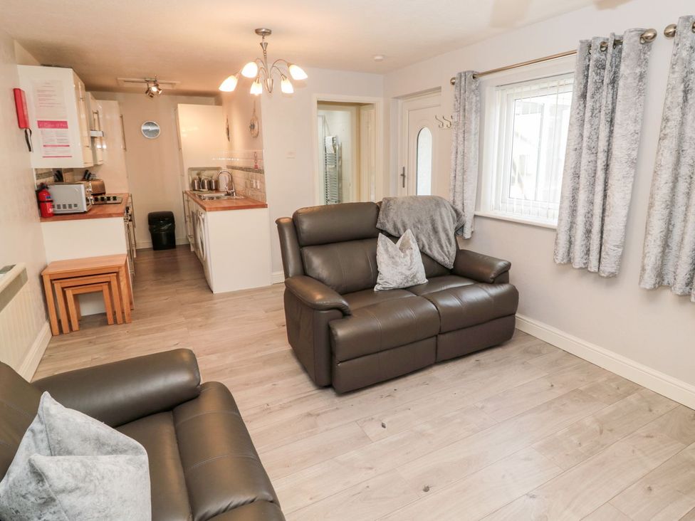 A living room with a sofa and kitchen counter at Primrose Cottage in Chathill