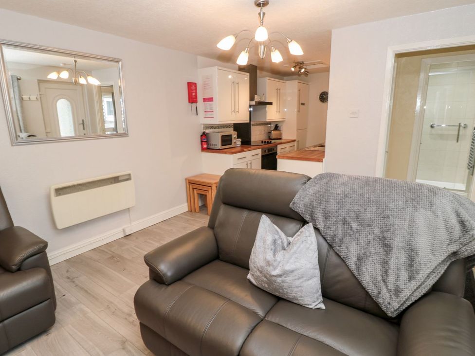 A living room with a sofa and kitchen area at Primrose Cottage in Chathill