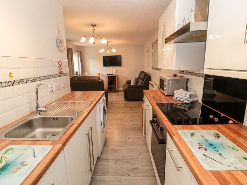 A kitchen with appliances and living area at Primrose Cottage Chathill