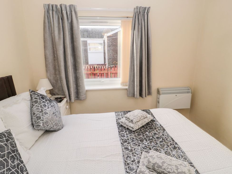 A bedroom with a bed and curtains at Primrose Cottage in Chathill