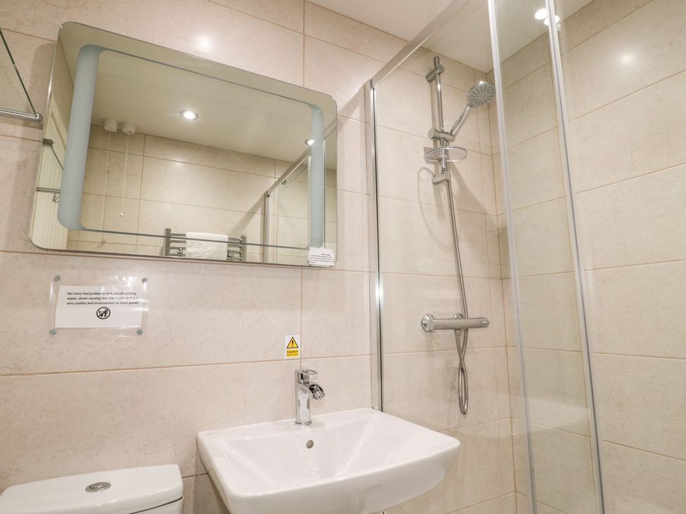A bathroom with a sink, shower, and mirror at Primrose Cottage in Chathill