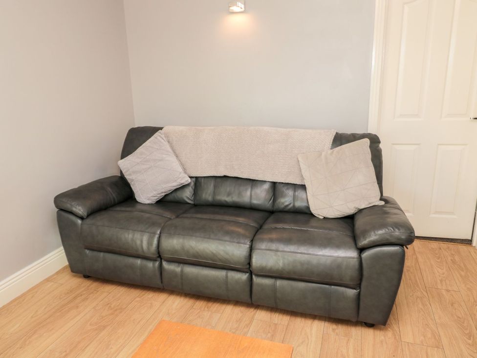 A sofa with cushions and a blanket in a living room at Megstone Chathill