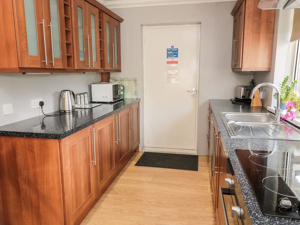 A kitchen with wooden cabinets and appliances at Megstone in Chathill