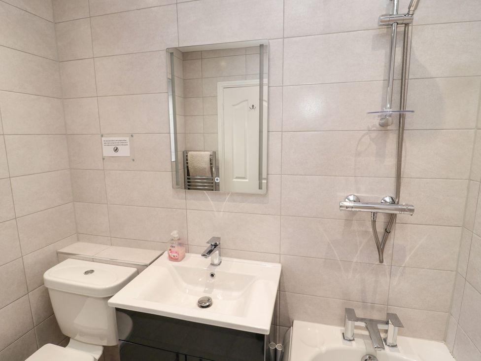 A bathroom with a toilet, sink, mirror and shower at Megstone in Chathill