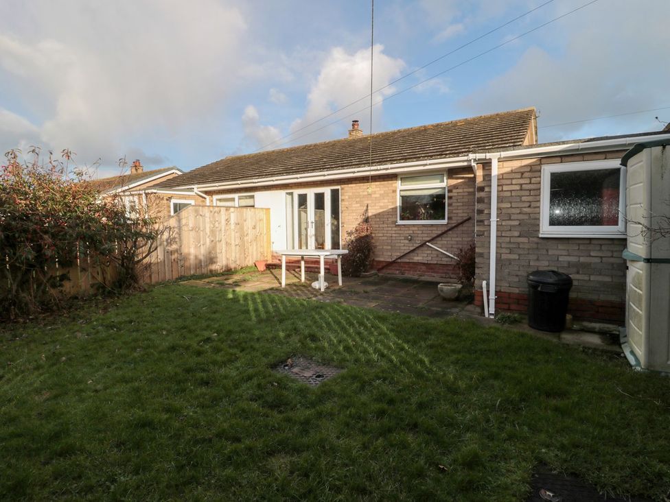 A garden area with grass, fence, and a house at Megstone in Chathill